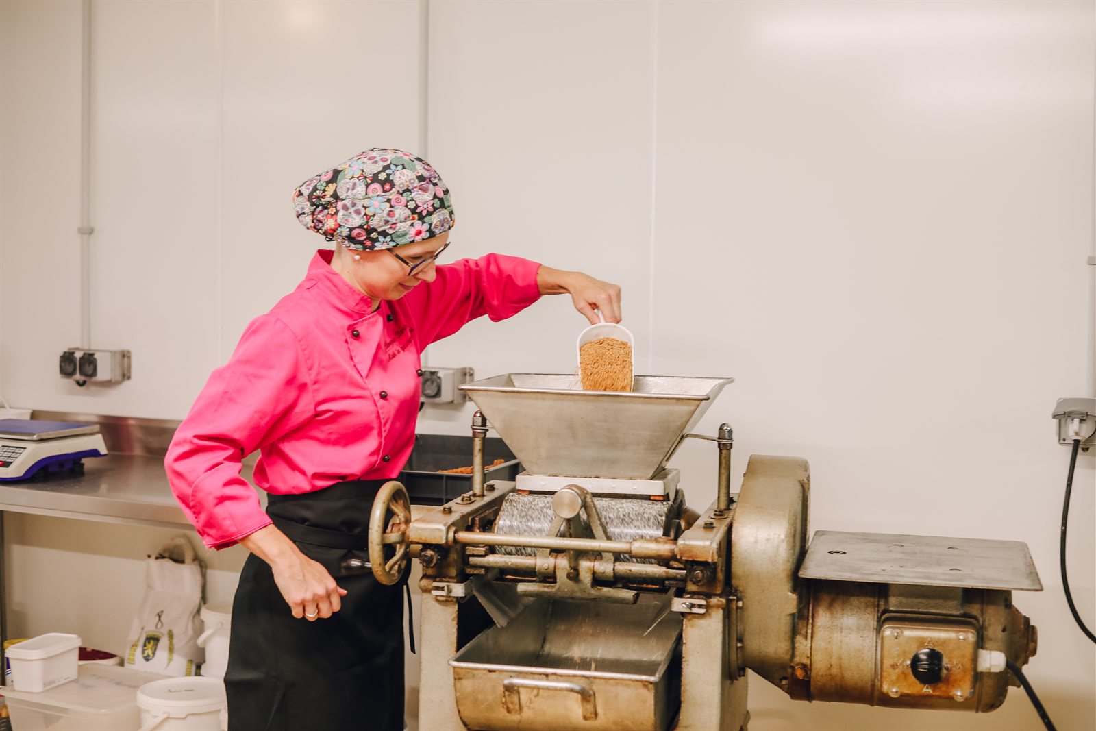 Clémence alimente la broyeuse à rouleaux de marbre avec les amandes caramélisées concassées