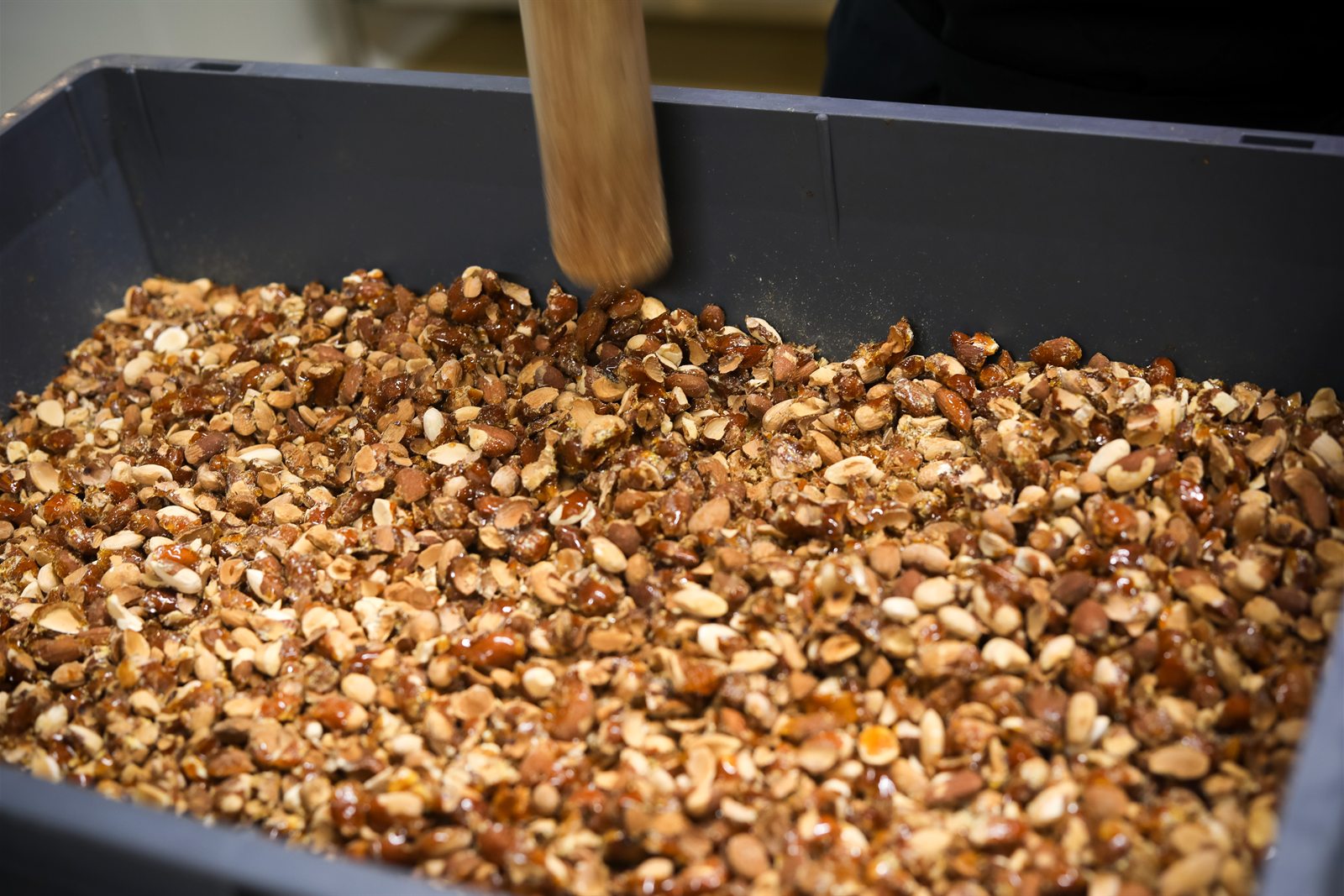 Des éclats d'amandes caramélisées, concassés, dans un grand bac