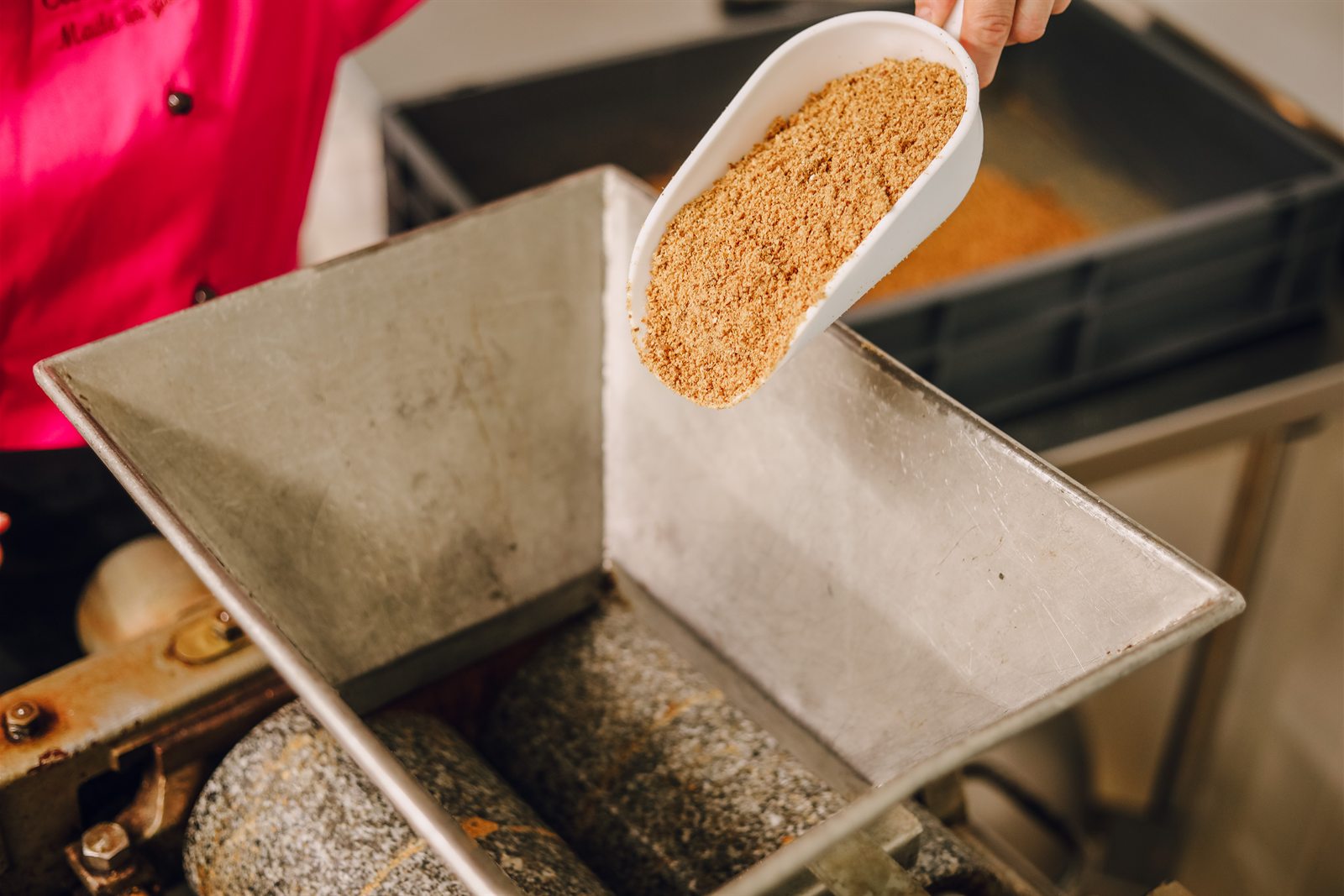 Les éclats d'amandes sont versés dans la trémie, au-dessus des rouleaux de marbre